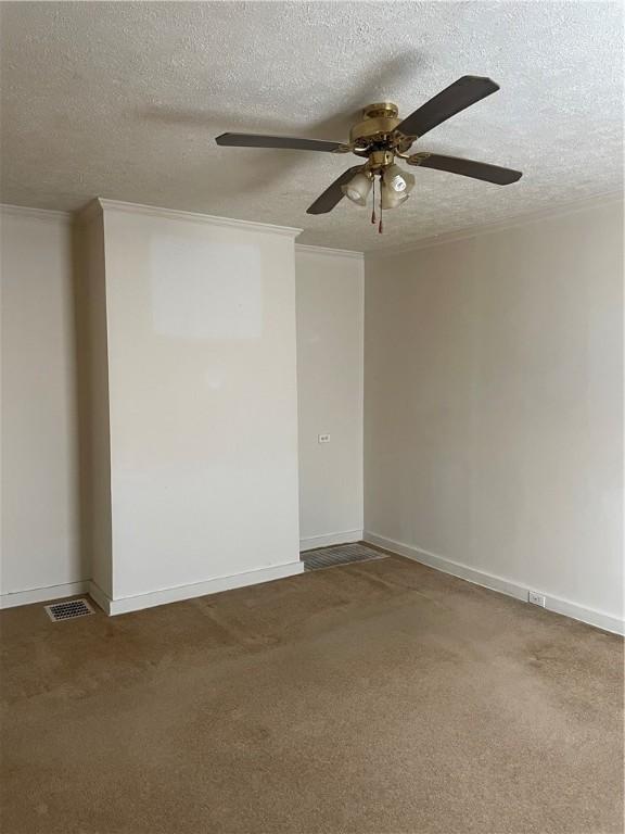 unfurnished room with carpet flooring, ceiling fan, crown molding, and a textured ceiling