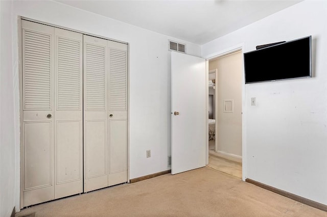 unfurnished bedroom featuring light carpet and a closet