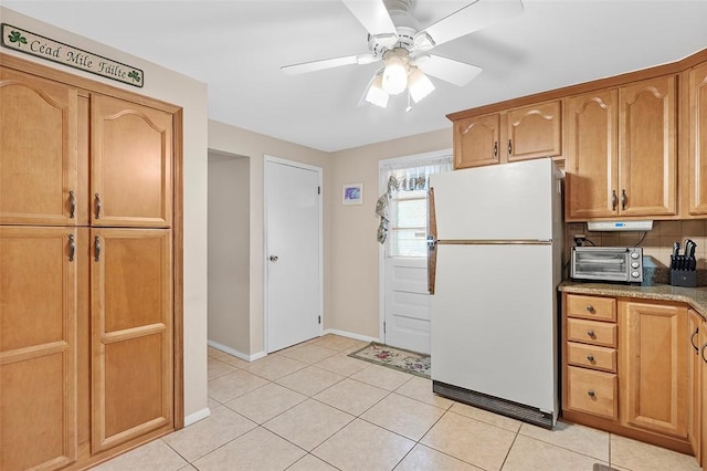 kitchen featuring light tile patterned floors, backsplash, white fridge, and ceiling fan