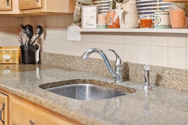 kitchen with decorative backsplash, light stone counters, and sink