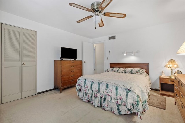 bedroom with a closet, ceiling fan, and light colored carpet