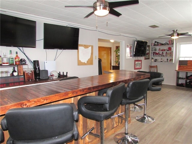 bar featuring ceiling fan, ornamental molding, wood counters, and light wood-type flooring