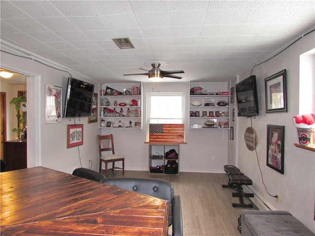 dining space featuring ceiling fan, built in shelves, and hardwood / wood-style flooring