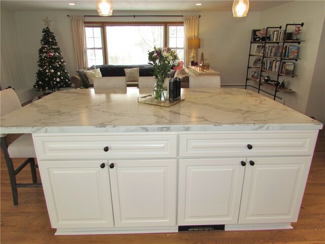 kitchen featuring light stone countertops, white cabinetry, a breakfast bar area, and a kitchen island