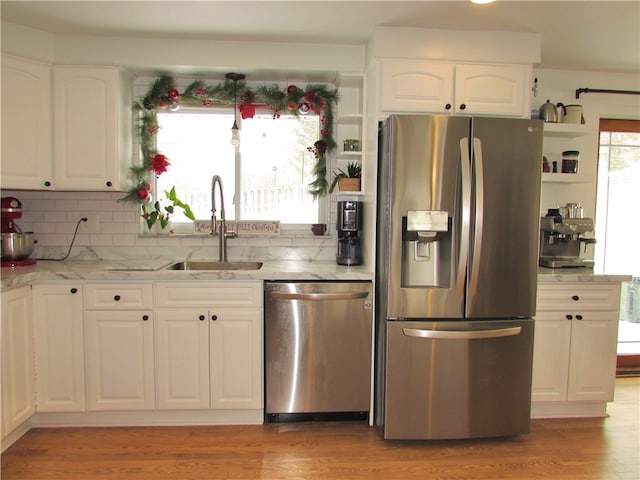 kitchen featuring white cabinetry, appliances with stainless steel finishes, decorative backsplash, light hardwood / wood-style flooring, and sink