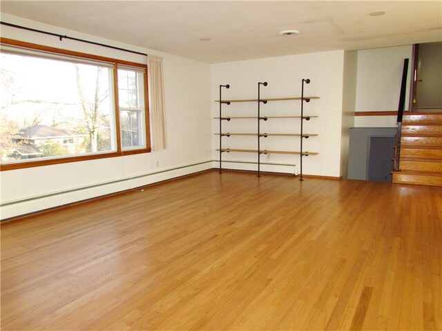 living room with light hardwood / wood-style floors, a baseboard heating unit, and a fireplace