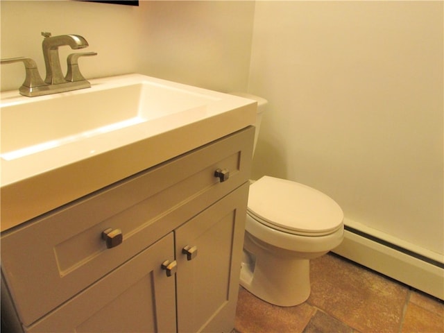 bathroom featuring vanity, toilet, baseboard heating, and stone finish flooring