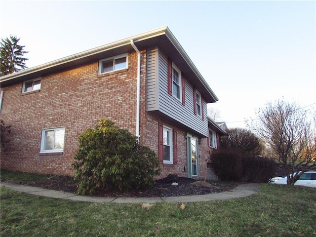 view of side of home featuring a yard and brick siding