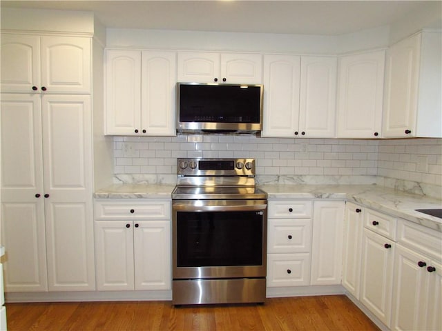 kitchen with backsplash, light wood-style flooring, white cabinets, and stainless steel appliances