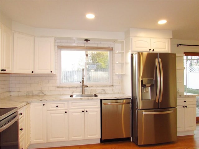 kitchen featuring white cabinetry, light stone counters, appliances with stainless steel finishes, and a sink