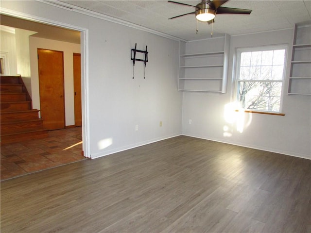 spare room with stairs, crown molding, ceiling fan, and wood finished floors