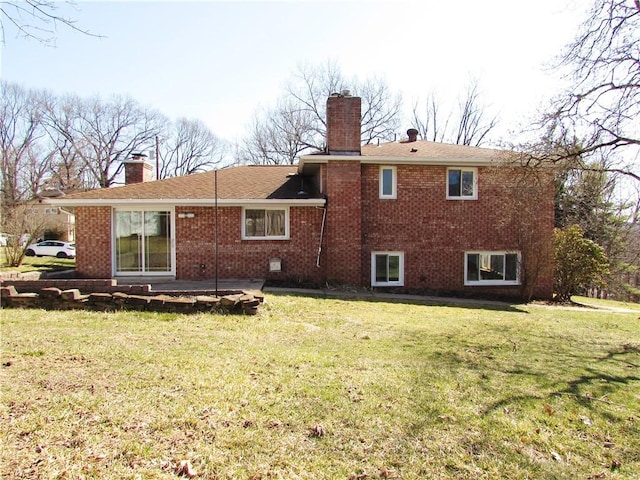 back of house featuring a patio, a lawn, brick siding, and a chimney