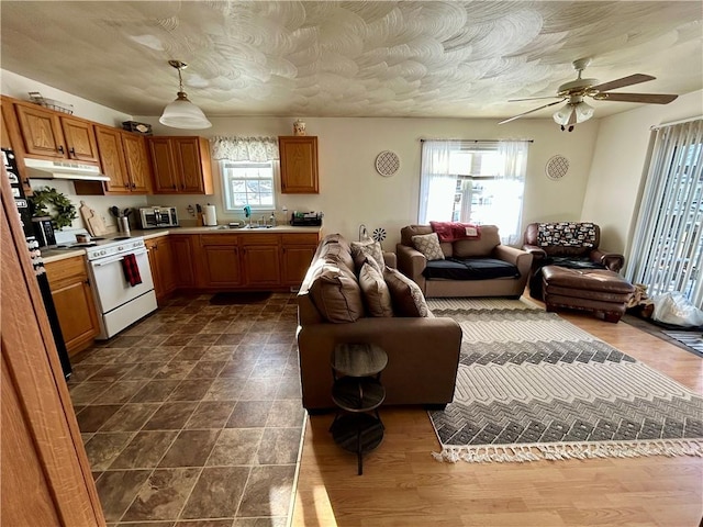 kitchen with ceiling fan, white range oven, hanging light fixtures, and sink