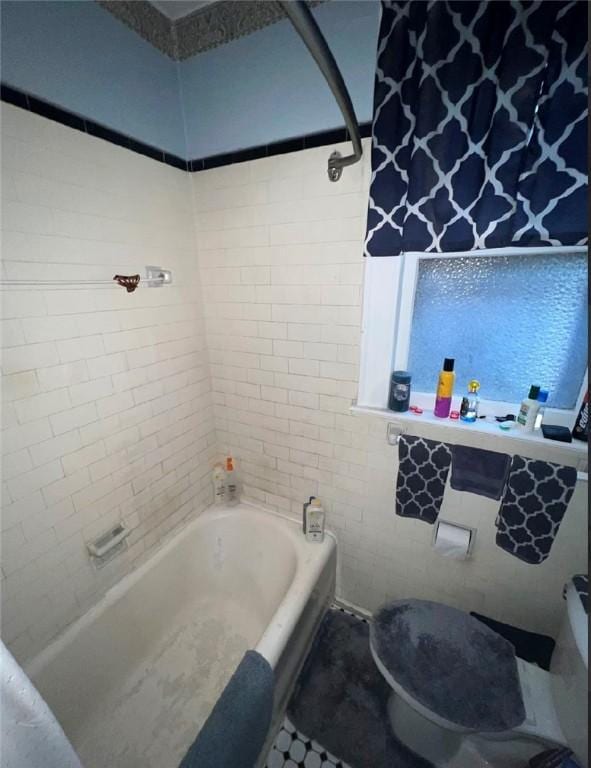 bathroom with toilet and tiled shower / bath