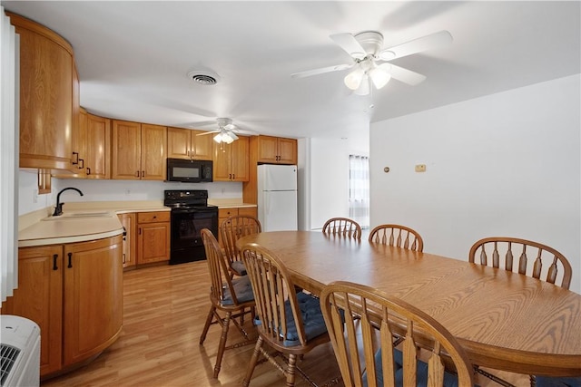 kitchen featuring sink, light hardwood / wood-style floors, ceiling fan, and black appliances