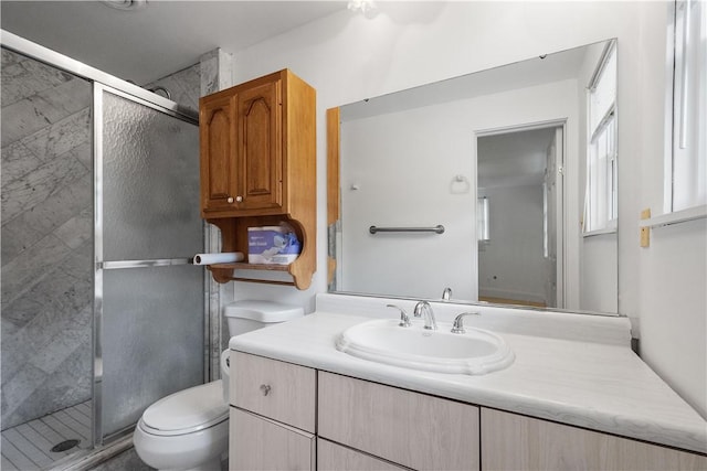 bathroom featuring a shower with door, vanity, and toilet