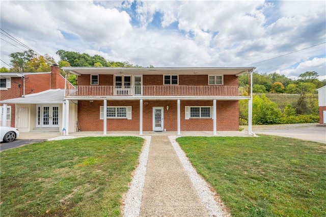 view of front of home with a balcony, a front yard, and french doors