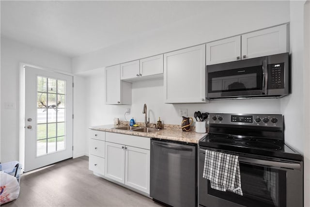 kitchen featuring white cabinetry, sink, stainless steel appliances, and light hardwood / wood-style flooring