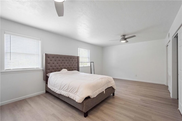 bedroom with ceiling fan, light wood-type flooring, and a closet