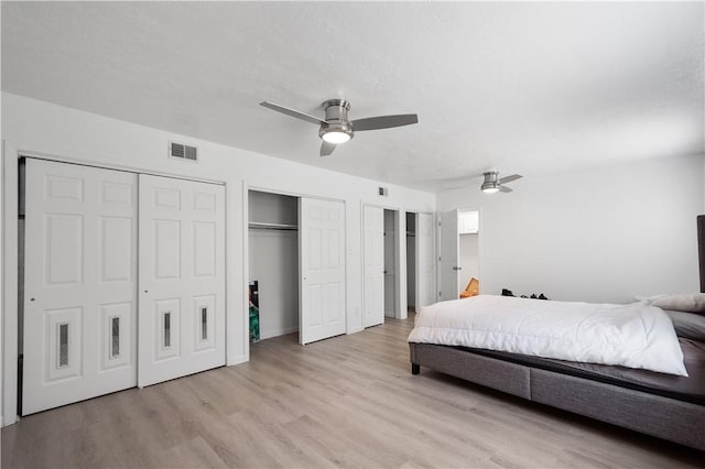 bedroom featuring multiple closets, ceiling fan, and light hardwood / wood-style flooring