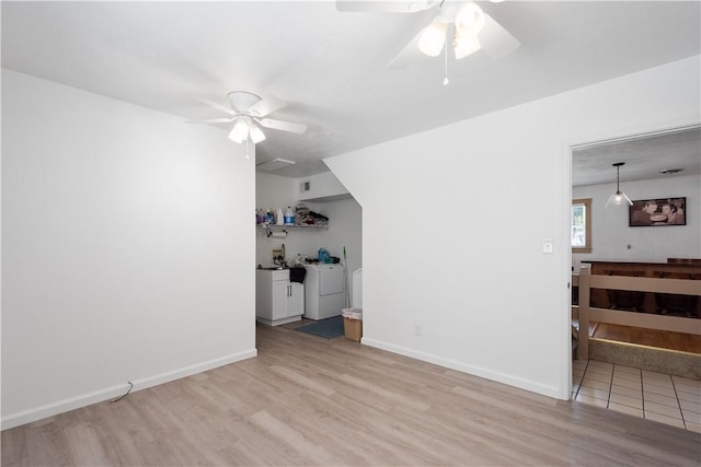 living room featuring independent washer and dryer, light hardwood / wood-style flooring, and ceiling fan