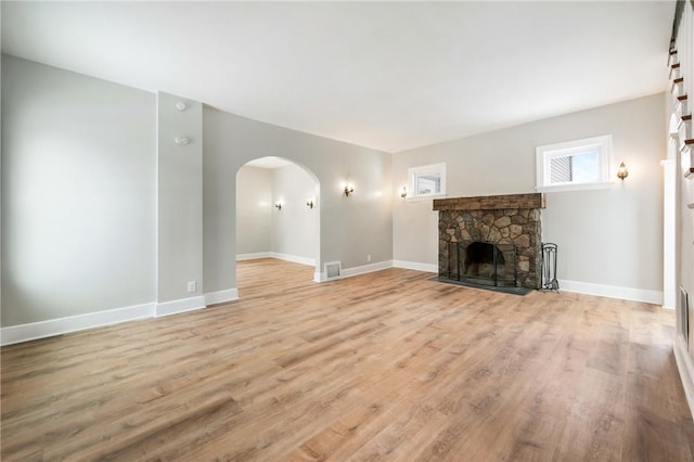 unfurnished living room with light hardwood / wood-style floors and a stone fireplace