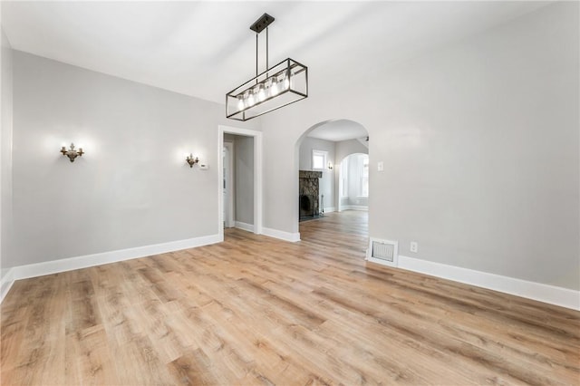 unfurnished dining area with a stone fireplace and light hardwood / wood-style flooring