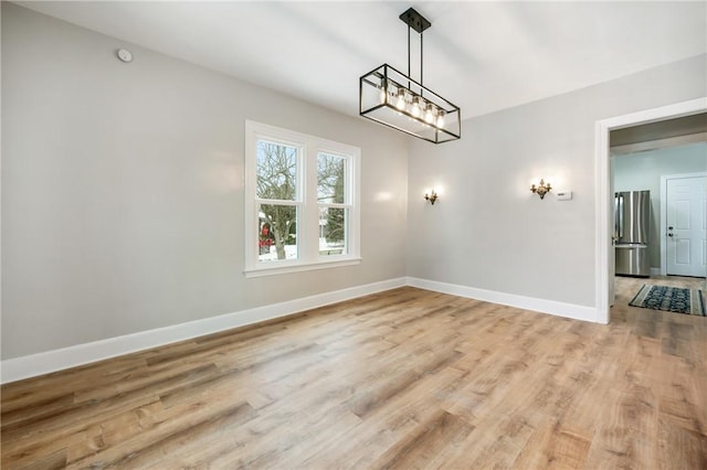 unfurnished dining area featuring light wood-type flooring and a chandelier