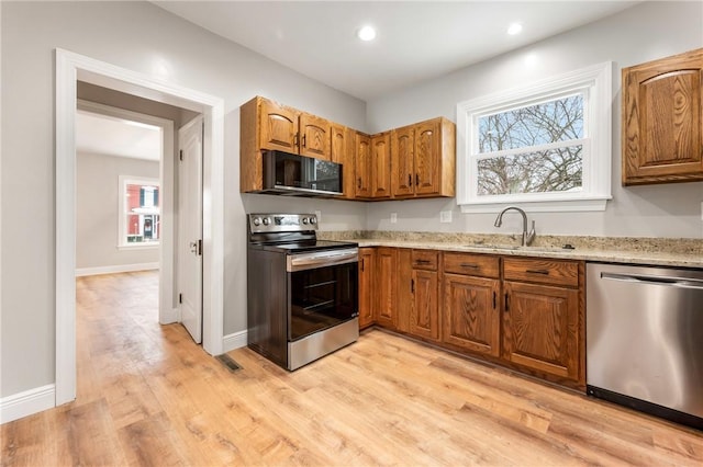 3134 Main St, West Middlesex Boro, PA 16159 - kitchen featuring stainless steel appliances, a sink, light wood-type flooring, brown cabinets, and light stone counters