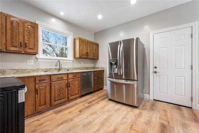 kitchen featuring light stone countertops, stainless steel appliances, light hardwood / wood-style floors, and sink