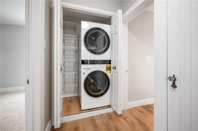 clothes washing area with wood-type flooring and stacked washing maching and dryer