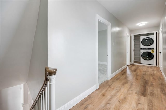 corridor with light hardwood / wood-style floors and stacked washer and clothes dryer