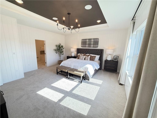 carpeted bedroom featuring a tray ceiling, an inviting chandelier, and ensuite bathroom