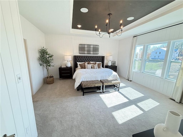 bedroom with a notable chandelier, light colored carpet, and a tray ceiling