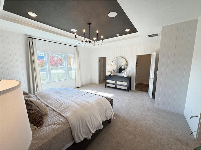 carpeted bedroom with a chandelier and a tray ceiling