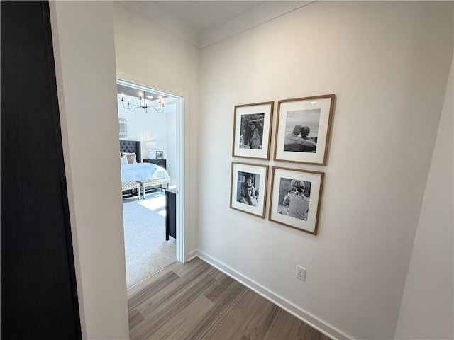 hallway with wood-type flooring and a chandelier