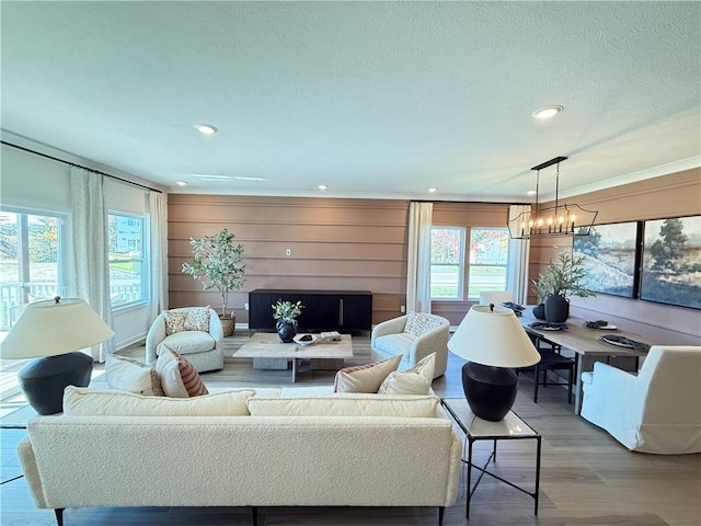 living room with light hardwood / wood-style flooring, a notable chandelier, and wood walls