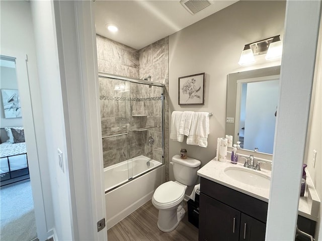 full bathroom featuring wood-type flooring, vanity, toilet, and bath / shower combo with glass door