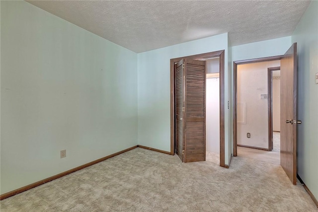 unfurnished bedroom featuring a textured ceiling, light carpet, and a closet