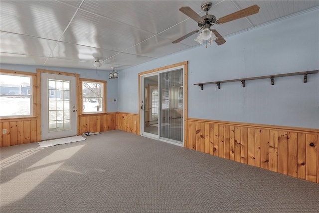 carpeted empty room featuring ceiling fan and wooden walls