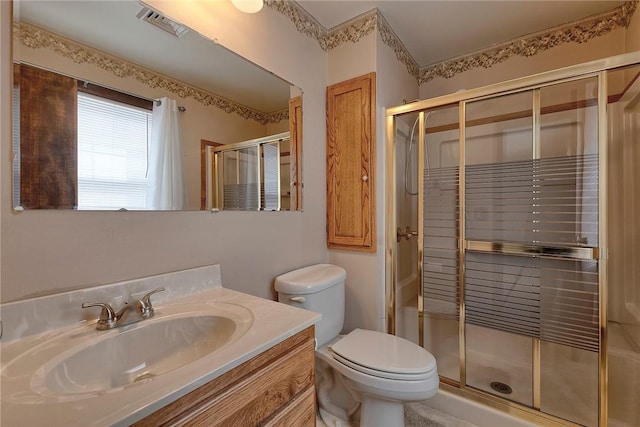 bathroom featuring vanity, a shower with shower door, and toilet