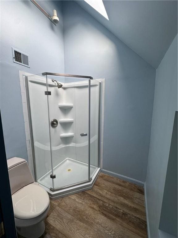 bathroom featuring lofted ceiling, toilet, wood-type flooring, and a shower with shower door