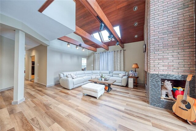 living room with vaulted ceiling with skylight, light hardwood / wood-style floors, a tiled fireplace, and wood ceiling