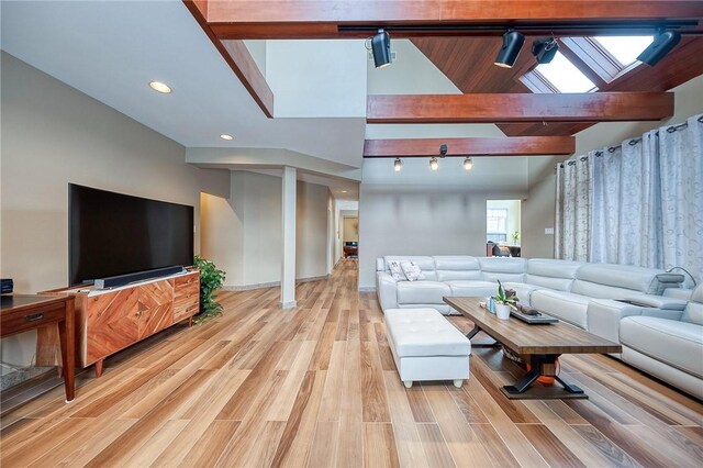 living room featuring beamed ceiling, rail lighting, high vaulted ceiling, and light hardwood / wood-style flooring