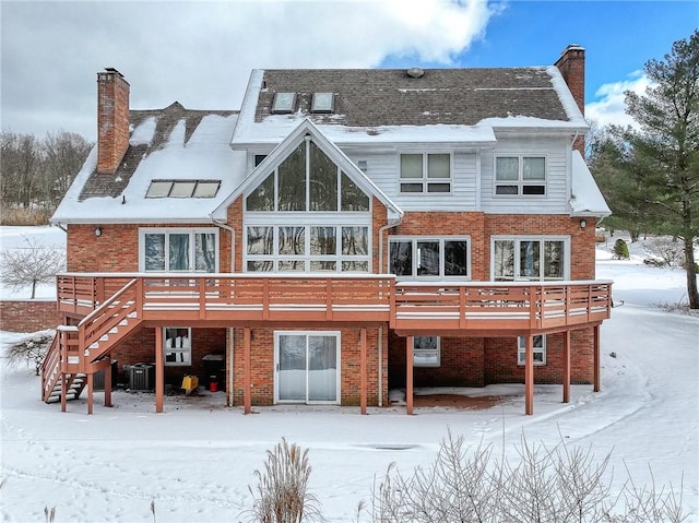 snow covered rear of property featuring central AC unit and a wooden deck