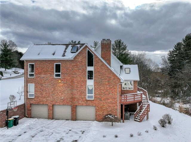 snow covered property featuring a deck and a garage