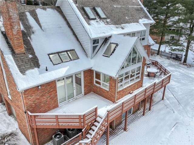 snow covered rear of property featuring a fire pit, a deck, and central air condition unit