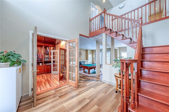 stairs featuring hardwood / wood-style flooring, billiards, and french doors