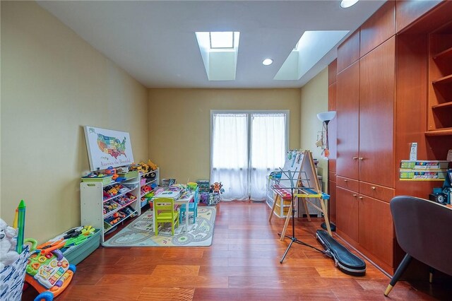 recreation room with light wood-type flooring and a skylight