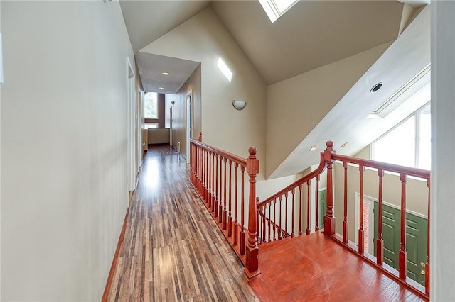 stairway with wood-type flooring, a skylight, and high vaulted ceiling